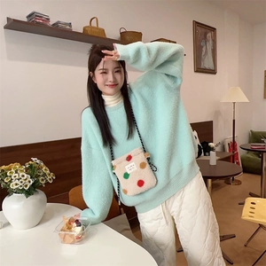 Détail d'un sac bandoulière en peluche à pois colorés porté avec un pull moelleux vert menthe
