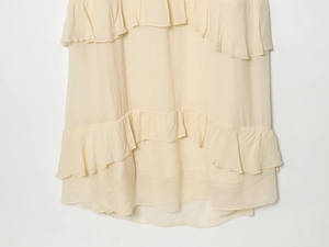 Close-up of tiered ruffle hem on cream chiffon midi dress with delicate pleated texture