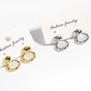 Détail de boucles d'oreilles ovales en nacre dorées et argentées sur cartes