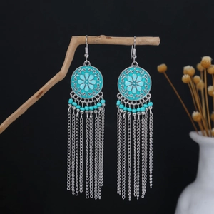 Detail of bohemian tassel earrings with turquoise beads hanging on a dry wooden branch