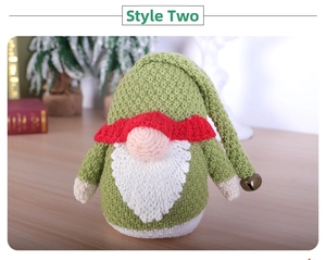 Close-up of a handmade knitted Christmas gnome with a green hat, red scarf, and metal bell