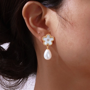 Detail of elegant gold beaded flower earrings with drop pearl on female model