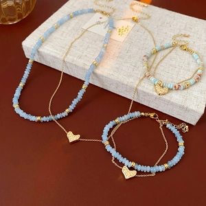 Detail view of heart pendant necklaces with light blue beads and golden metal accents