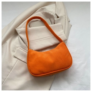 Detailed texture of orange corduroy baguette bag on a beige blazer background