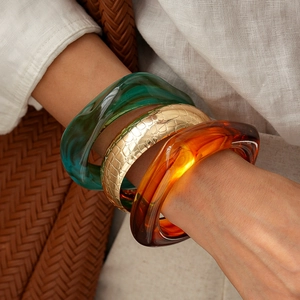 Retro acrylic resin and gold-embossed metal wide bangles stacked on a model's wrist