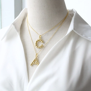 Polished 18K gold letter A and C pendant necklaces with textured beaded surface design