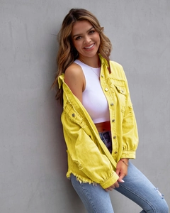 Detail der gelben Jeansjacke mit ausgefranstem Saum und langen Ärmeln am Modell