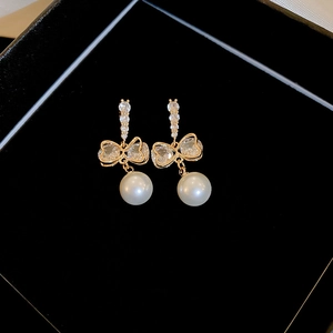 Boucles d'oreilles nœud élégantes avec perles d'imitation et zircons sur fond noir