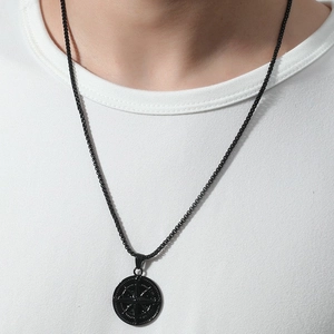 Close-up of a black compass pendant necklace with intricate engraved details on a model