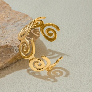 Detailed view of a gold spiral open cuff bracelet on a natural rock surface