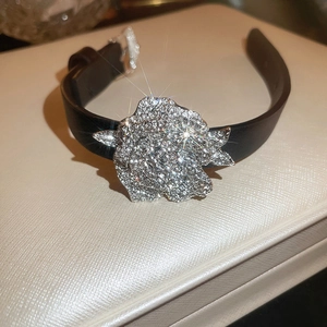 Makroaufnahme einer funkelnden Strass-Rose an einem schwarzen Lederarmband-Armreif