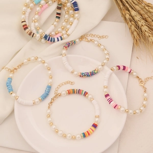 Detail of colorful polymer clay and pearl bohemian bracelets on white ceramic plate