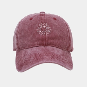 Détail de la broderie soleil sur une casquette vintage en coton délavé bordeaux