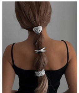 Detailed view of silver heart clip and textured metal hair ties on a ponytail braid