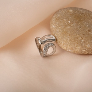 Irregular silver titanium steel ring with zircon on peach silk and pebble backdrop