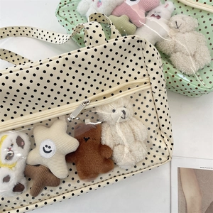 Close-up of canvas tote bag with polka dots and transparent PVC front pocket with toys