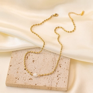 Elegant gold titanium steel necklace with natural freshwater pearl on a stone block
