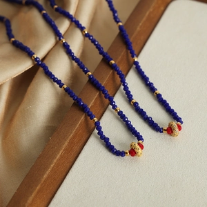 Double-layered blue stone beaded necklace with gold accents and circular pendant