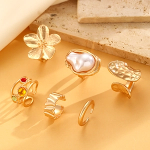 Detail of six gold vintage rings featuring baroque pearl, flower design and colorful stones