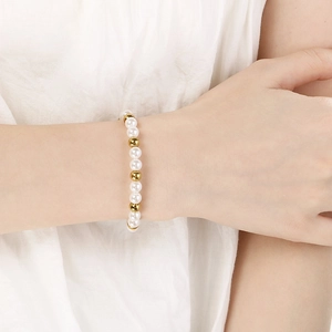 Elegantes Armband aus Perlen und Goldperlen am Handgelenk für einen minimalistischen Look