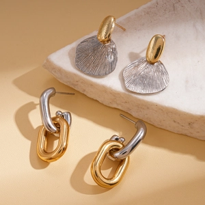 Geometric oval shell earrings in gold and silver metal finish on a stone background