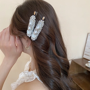 Detailed view of pearl hair clips on wavy hair featuring elegant rectangle design