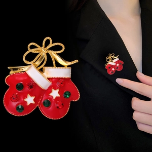 Broche gants de Noël en émail rouge avec nœud doré et cristaux sur veste noire