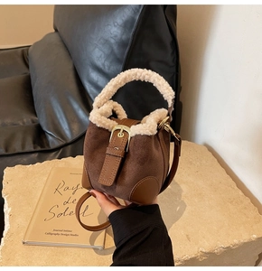 Detail of a mini brown suede bucket bag with white plush faux fur trim and leather strap