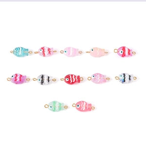 Macro view of twelve colorful handmade glass fish pendants with golden metal loops