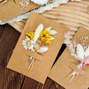 Handmade kraft paper greeting cards with dried flower bouquets on a rustic wood background