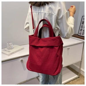Detail of red oversized nylon tote bag with adjustable shoulder strap and dual handles