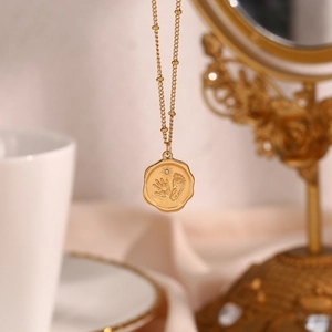 Détail du collier doré avec pendentif empreinte de nouveau-né et petit zircon brillant