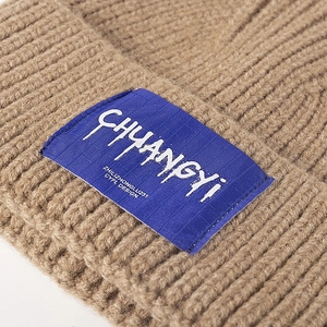 Thick camel knitted beanie hat with stylish woven label and chunky ribbed texture