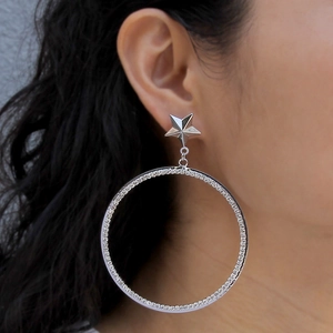 Detailed close-up of a silver oversized hoop earring with star stud and crystal inlay