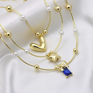 Three gold layered necklaces with white pearls, star and blue gemstone bow heart charms