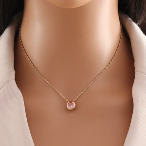 Close-up of gold chain necklace featuring a delicate round pink zircon stone pendant
