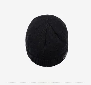 Detail view of black beanie featuring vertical ribbed knit texture and rectangular woven label