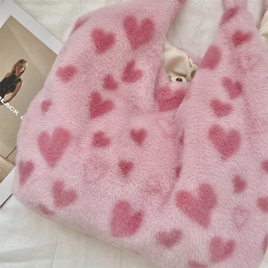 Close-up of soft pink faux fur shoulder bag with heart patterns and fabric lining detail