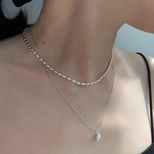 Close-up of double layered S925 silver necklace with olive beads and teardrop pendant
