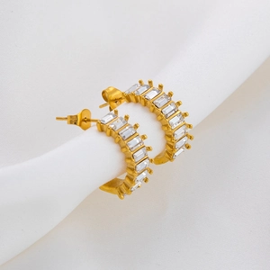 Close-up of golden half-hoop earrings with channel-set rectangular baguette zircons