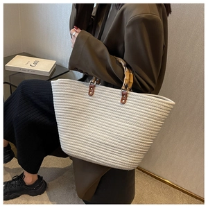 Detail showing handwoven cotton tote bag with natural bamboo handle and brown leather accents