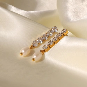 Détail de boucles d'oreilles en or 18K avec zircons blancs et une perle en forme de goutte