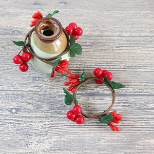 Close-up of red berry wreath napkin rings with green leaves on wooden background