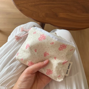Close-up of floral cotton coin purse with white zipper and a pink cord puller detail