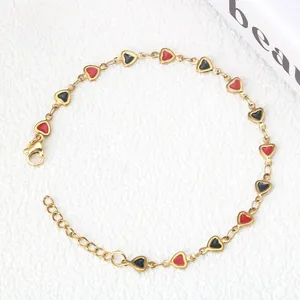 Dettaglio del bracciale dorato con ciondoli a cuore smaltati rossi e neri e chiusura a moschettone