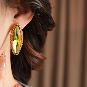 Close-up of a large yellow marquise-cut crystal earring with gold textured metal edge