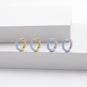 Detailed view of silver and gold enamel hoop earrings with light blue drip oil finish