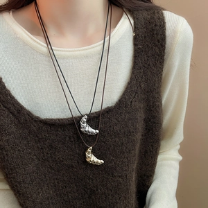 Detailed view of croissant-shaped gold and silver pendants on adjustable cords