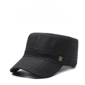 Close-up of black flat top cap with side golden metal logo detail and textured fabric