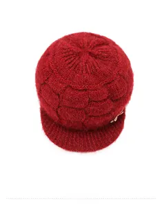 Top view of a thick dark red knitted winter hat with visor and golden bow detail
